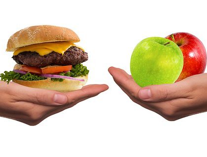 hands showing a burger vs two apples alternative diet
