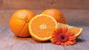 cut up orange next to two whole oranges and a daisy