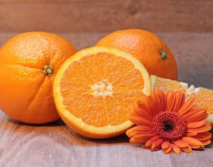cut up orange next to two whole oranges and a daisy